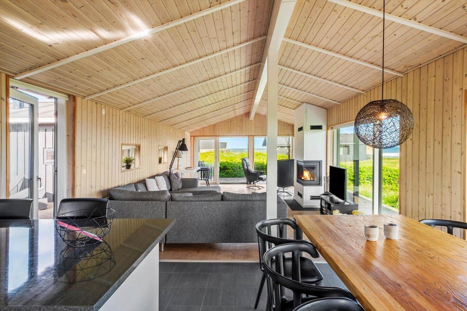 Wohn- und Essbereich mit Holzverkleidung, Kamin und großem Fensterblick.