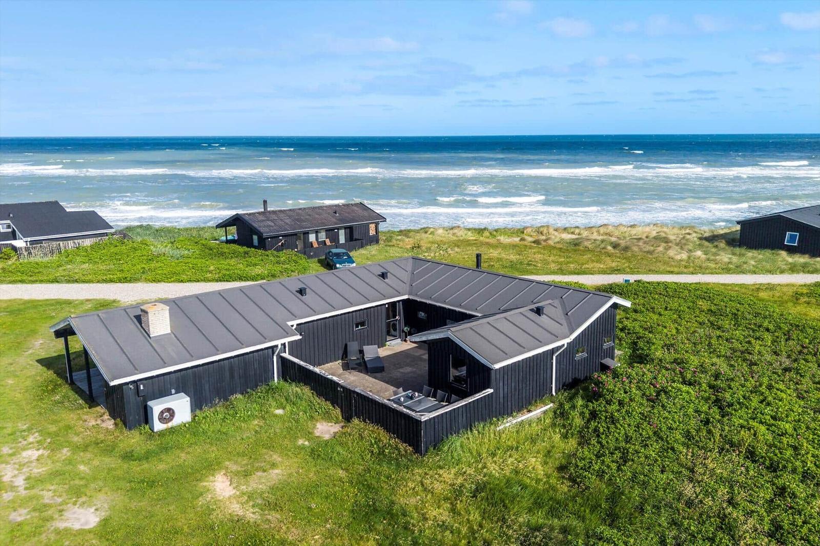 Moderne Strandhaus mit Terrasse und Meerblick. Umgeben von Gras und Dünen.