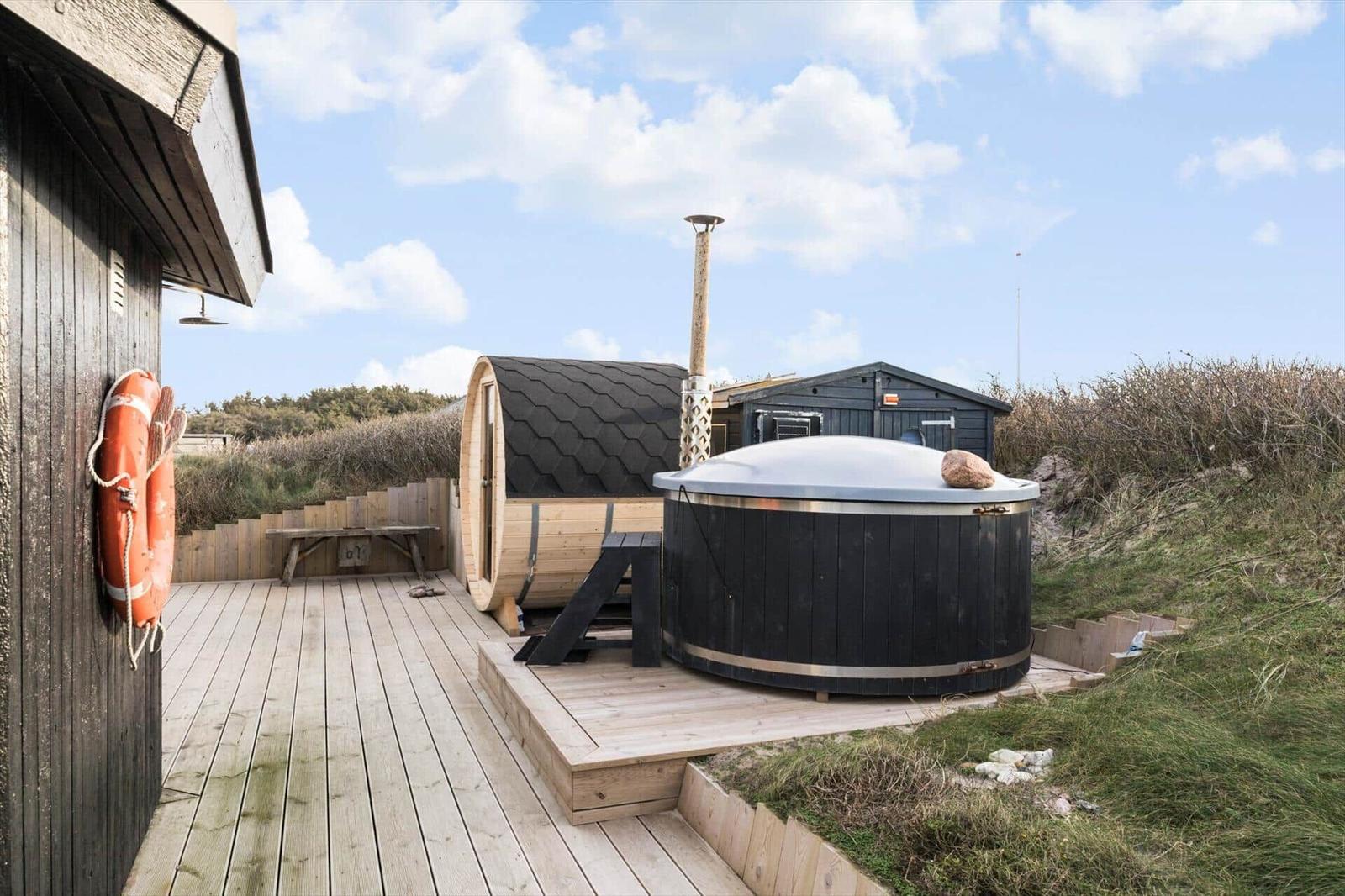 Terrasse mit Whirlpool und Holzsauna im Freien.