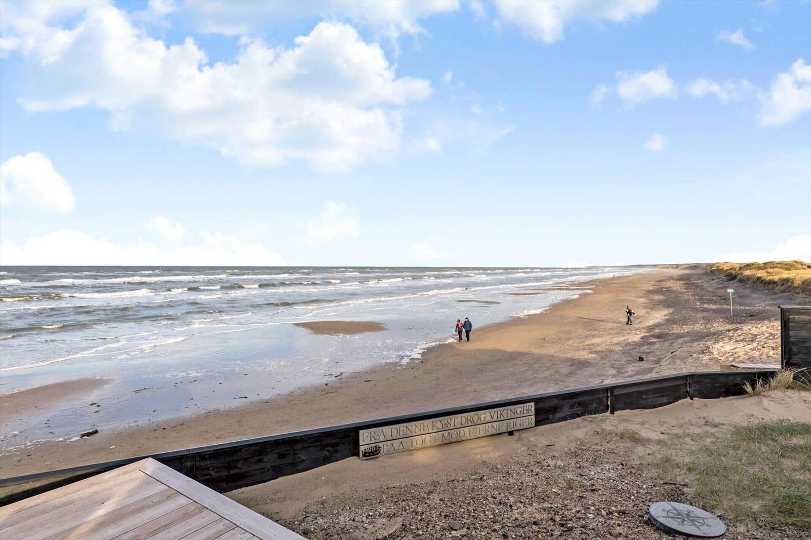Strand mit Wellen, Menschen spazieren entlang der Küste.