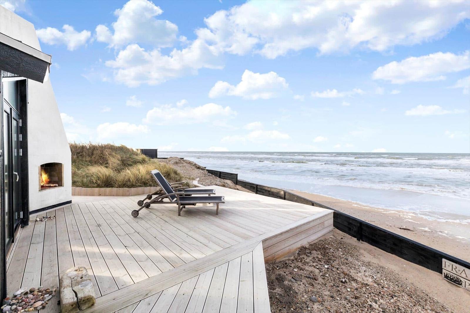 Terrasse mit Liegestühlen und Meerblick. Holzdeck und Strand direkt daneben.