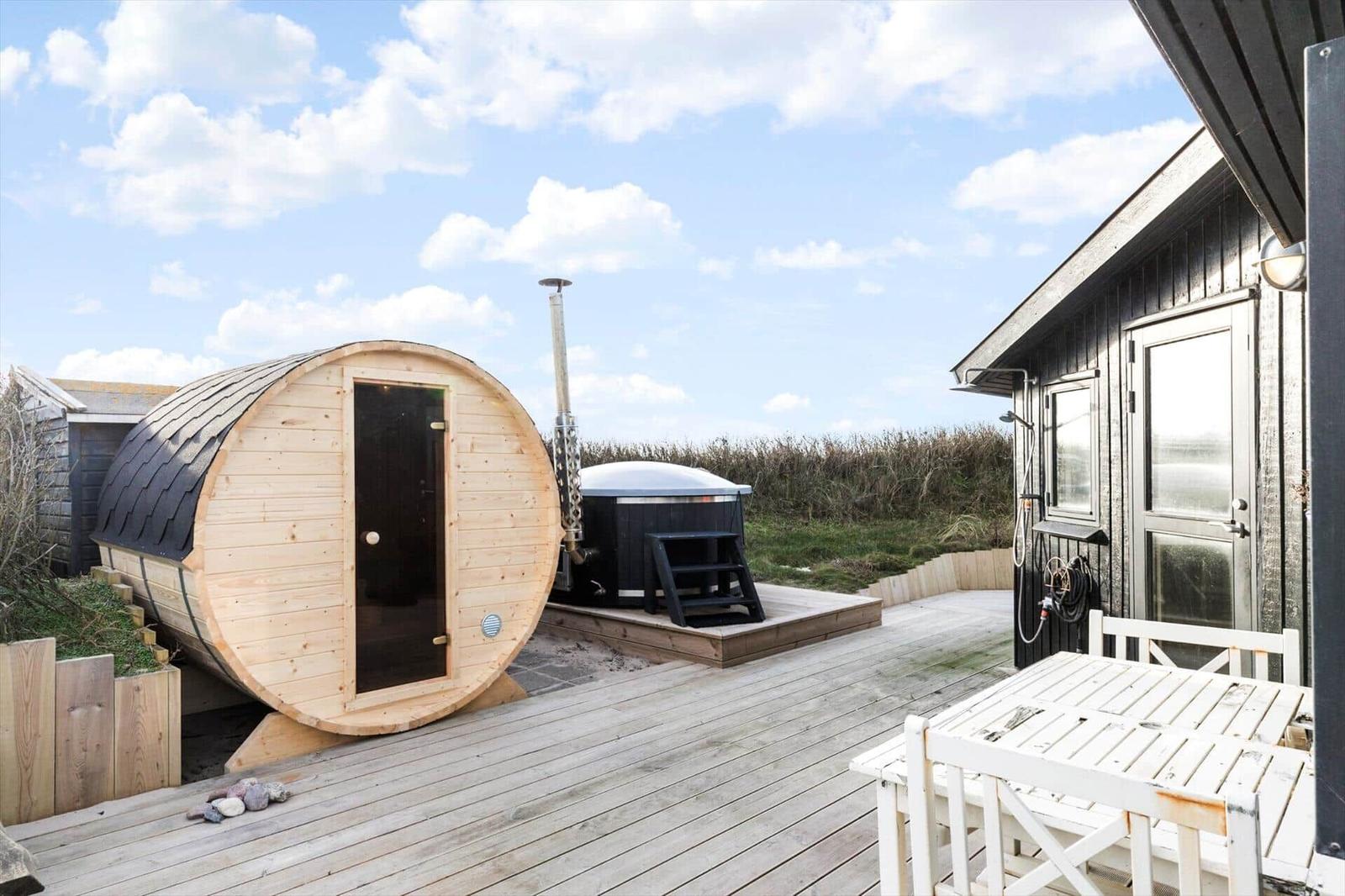Außenbereich mit Sauna, Whirlpool und Holzterrasse neben einem Haus.