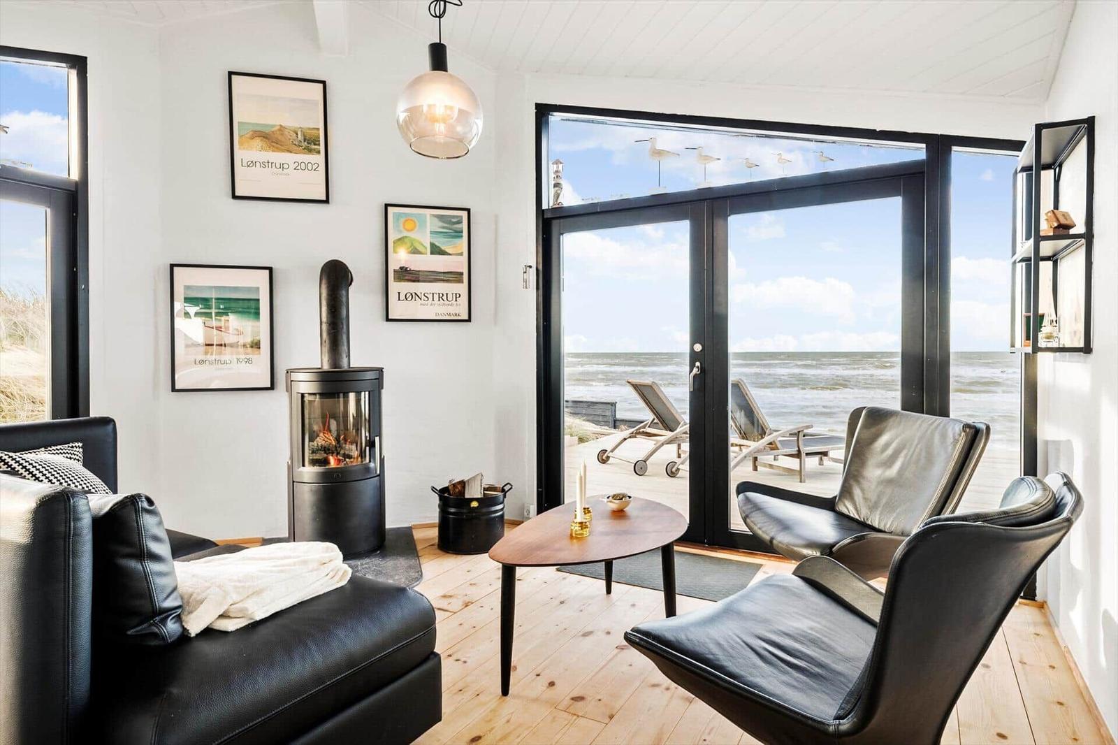 Wohnraum mit Sitzgelegenheiten, Kamin und Blick aufs Meer.