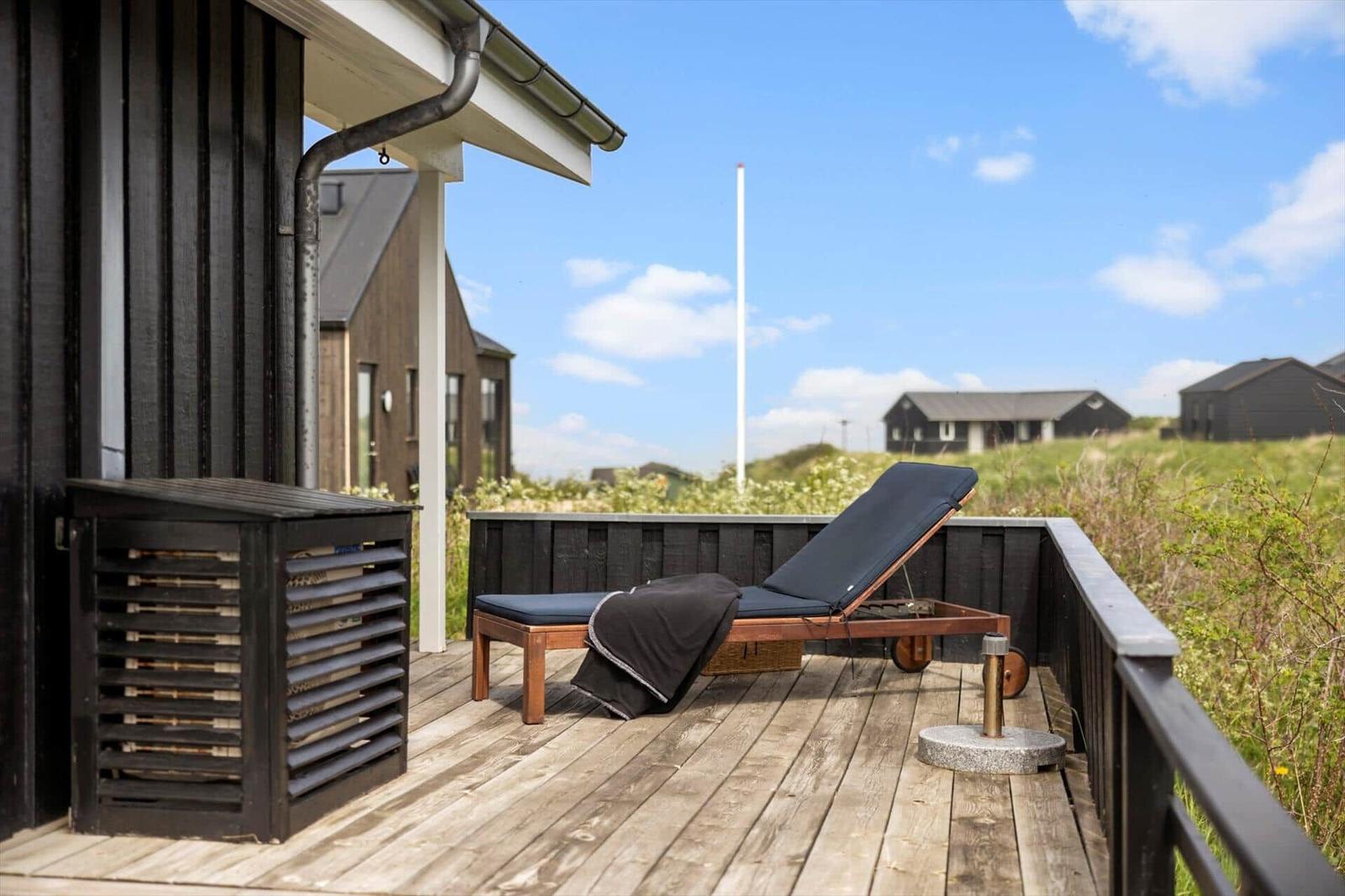 Terrasse mit Liegestuhl und Blick auf grüne Landschaft und Häuser
