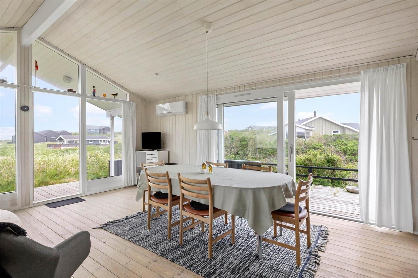 Esszimmer mit Tisch, Stühlen und Blick auf die Landschaft.