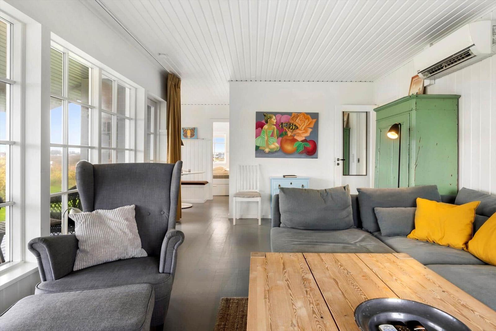 Wohnzimmer mit grauem Sofa, Holztisch und grünem Schrank.