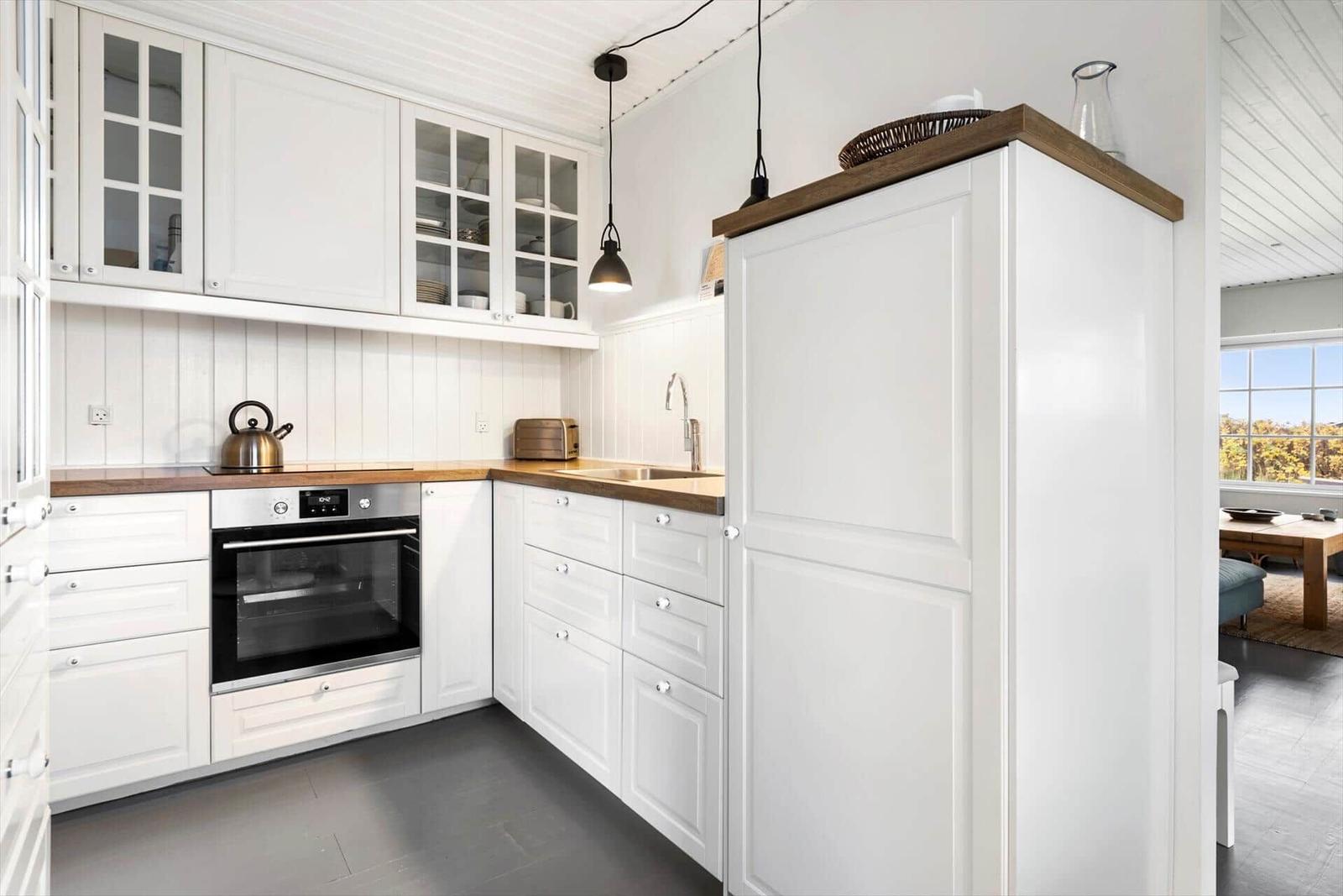 Küche mit weißen Schränken, Holzoberflächen und integriertem Backofen.