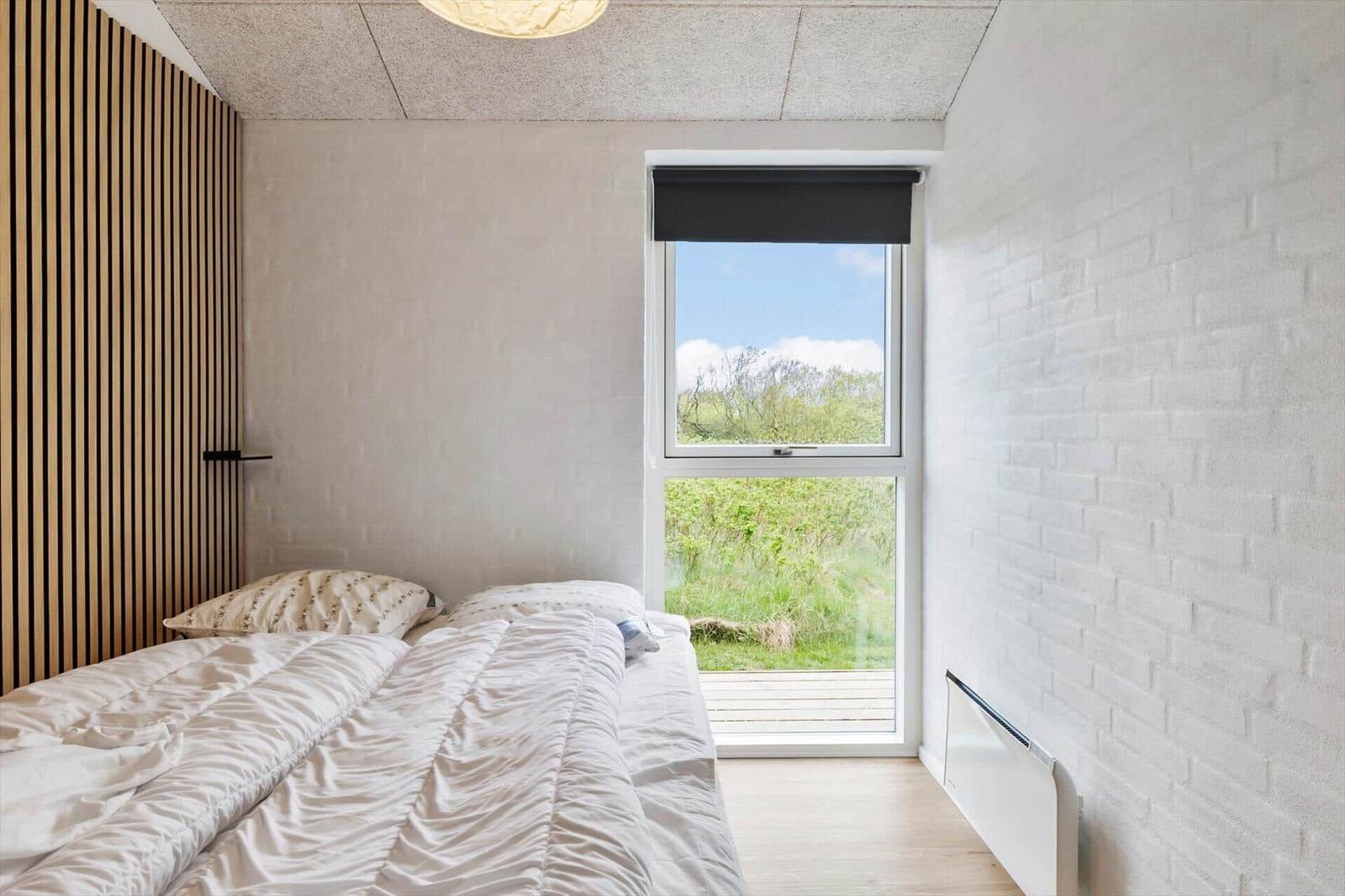 Schlafzimmer mit Bett, Fenster und Holzwand