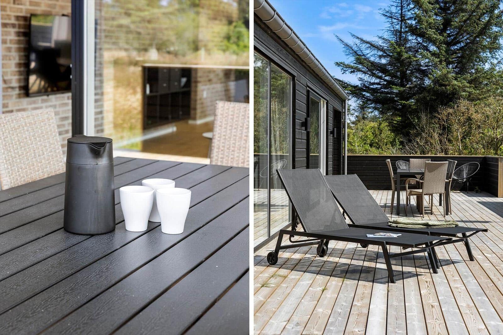 Terrasse mit Liegestühlen und Tisch. Blick auf Haus und Bäume.