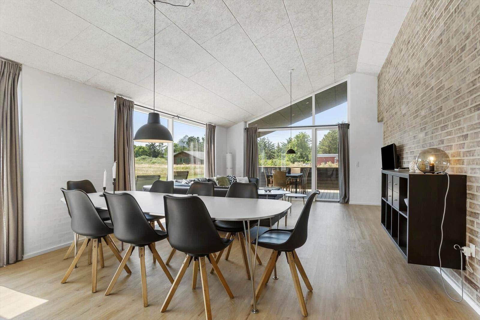 Esszimmer mit Tisch und Stühlen, große Fenster und Holzboden.