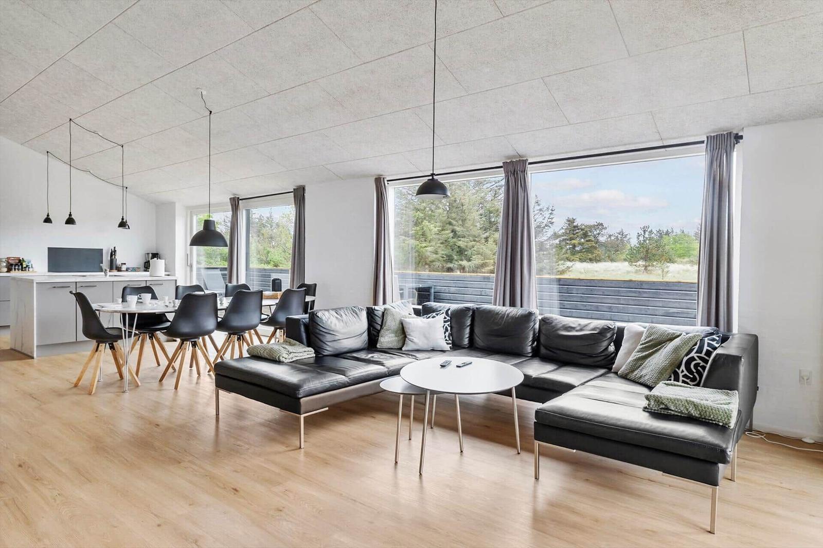 Wohn- und Essbereich mit großem Sofa, Esstisch und Fenster zur Außenterrasse.