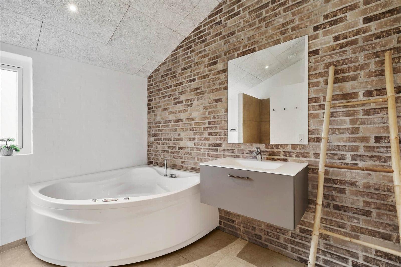 Bad mit Whirlpool, Backsteinwand, Spiegelschrank und Bambusleiter