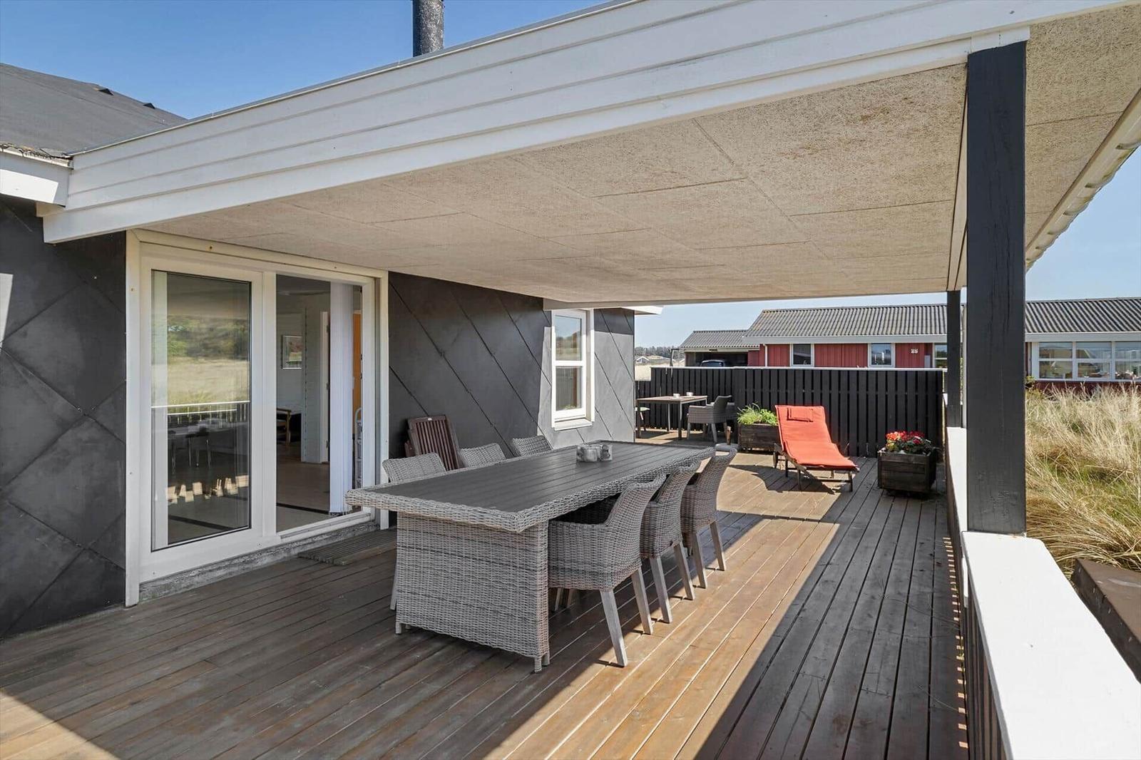 Terrasse mit Tisch, Stühlen und Liegestuhl unter Dach