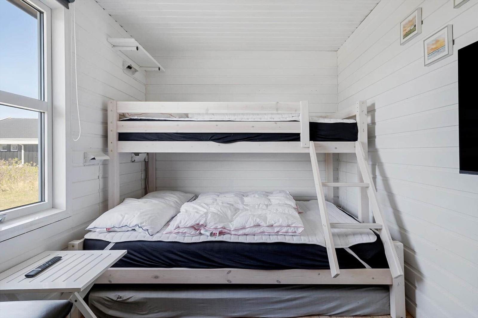 Zimmer mit Doppelstockbett, Fenster und Wandbildern.