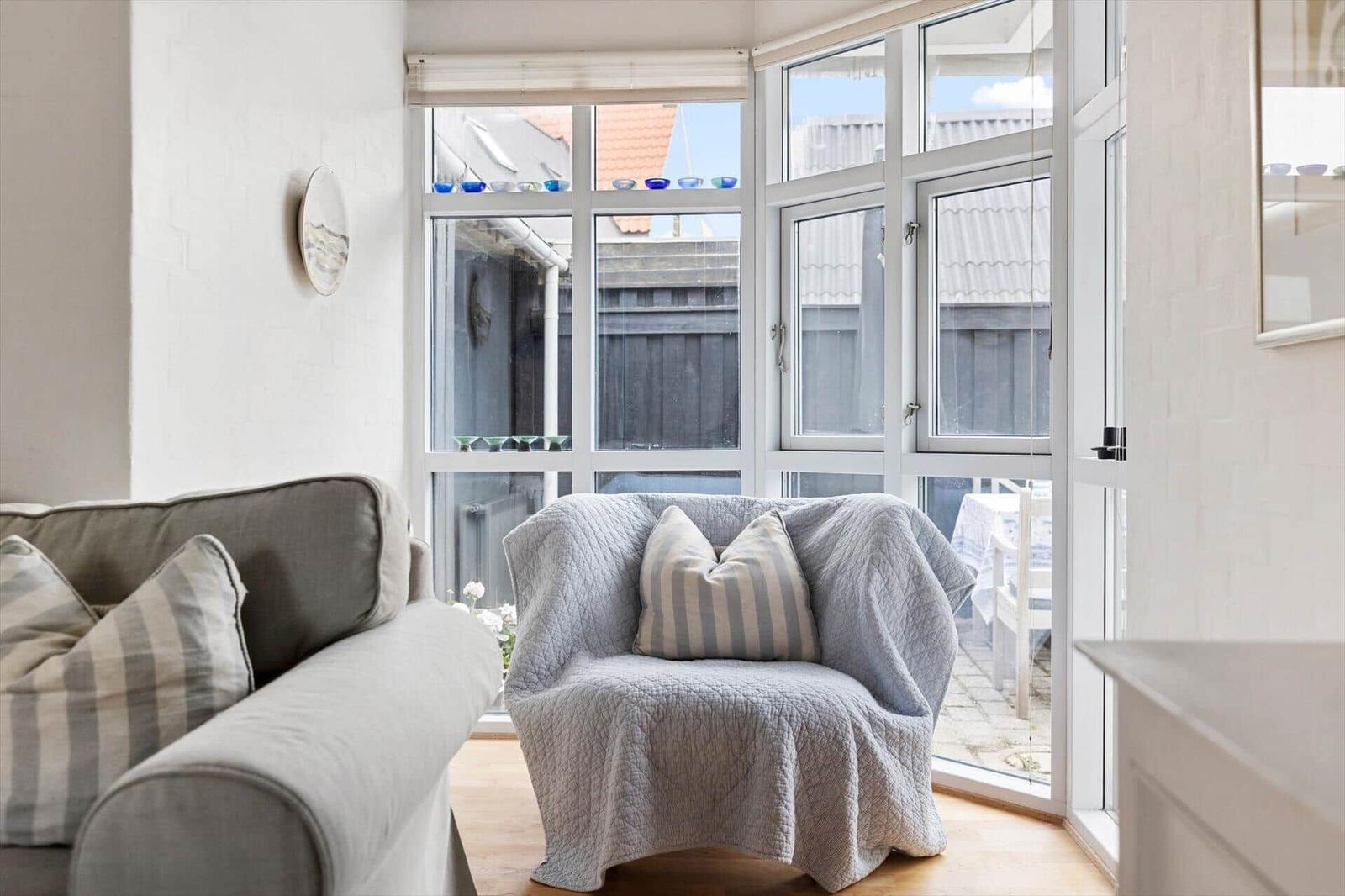 Ein Wohnzimmer mit Sitzmöbeln und großen Fenstern zum Garten.