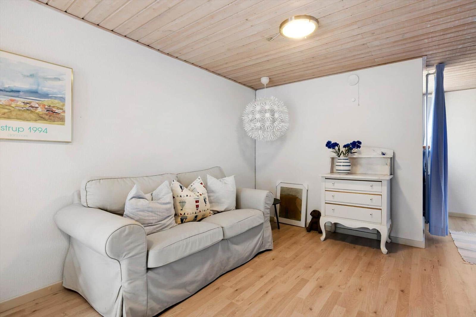 Wohnzimmer mit Sofa, Kleiderschrank und Holzboden.