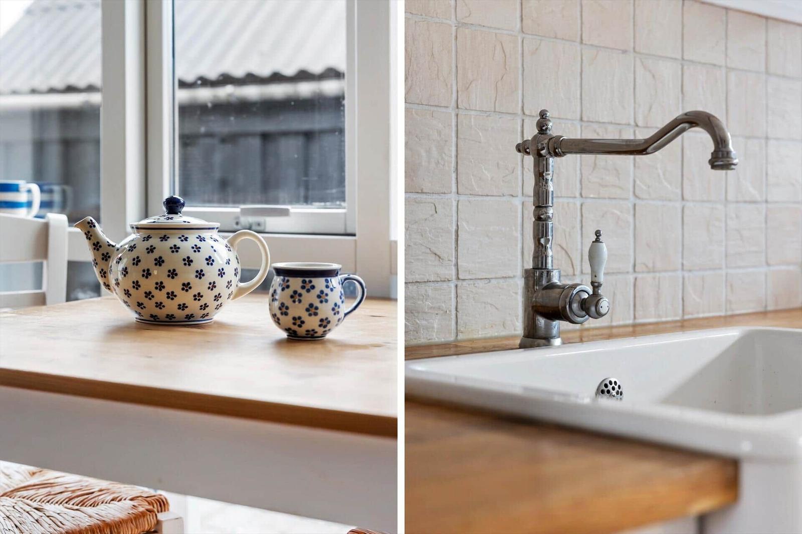 Küchenzeile mit Keramikspüle und klassischem Wasserhahn. Holzoberfläche und Fenster mit Blick draußen.