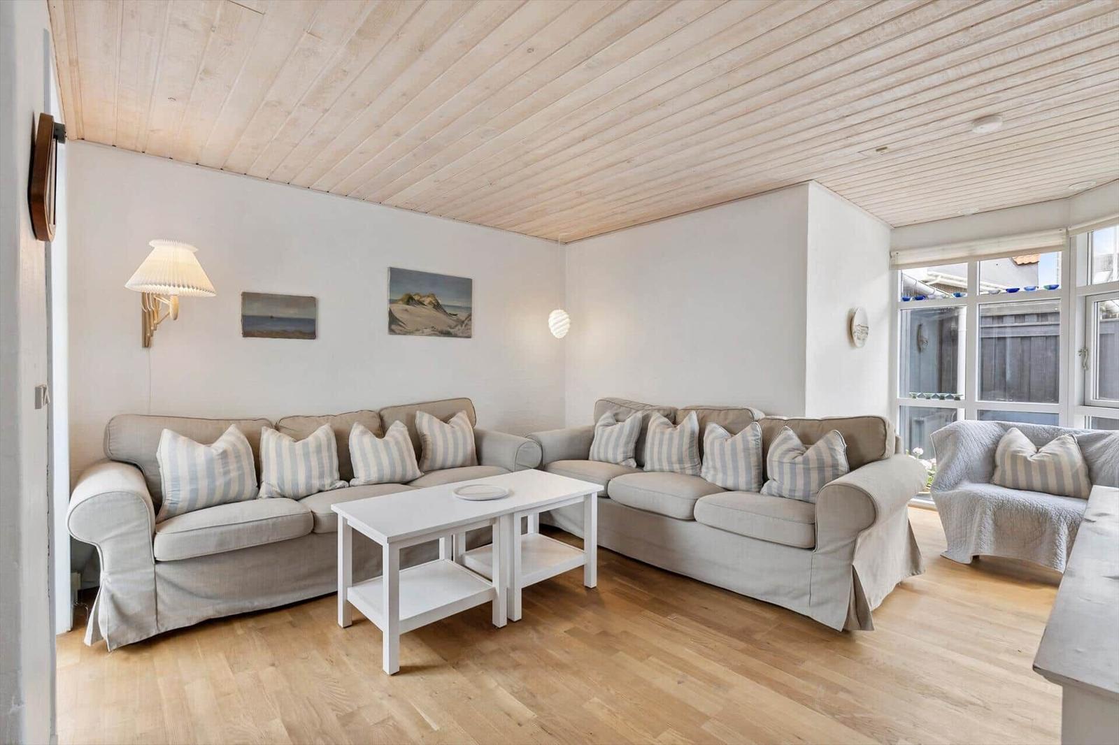 Wohnzimmer mit zwei Sofas, Tisch und Holzboden. Decke aus Holz.