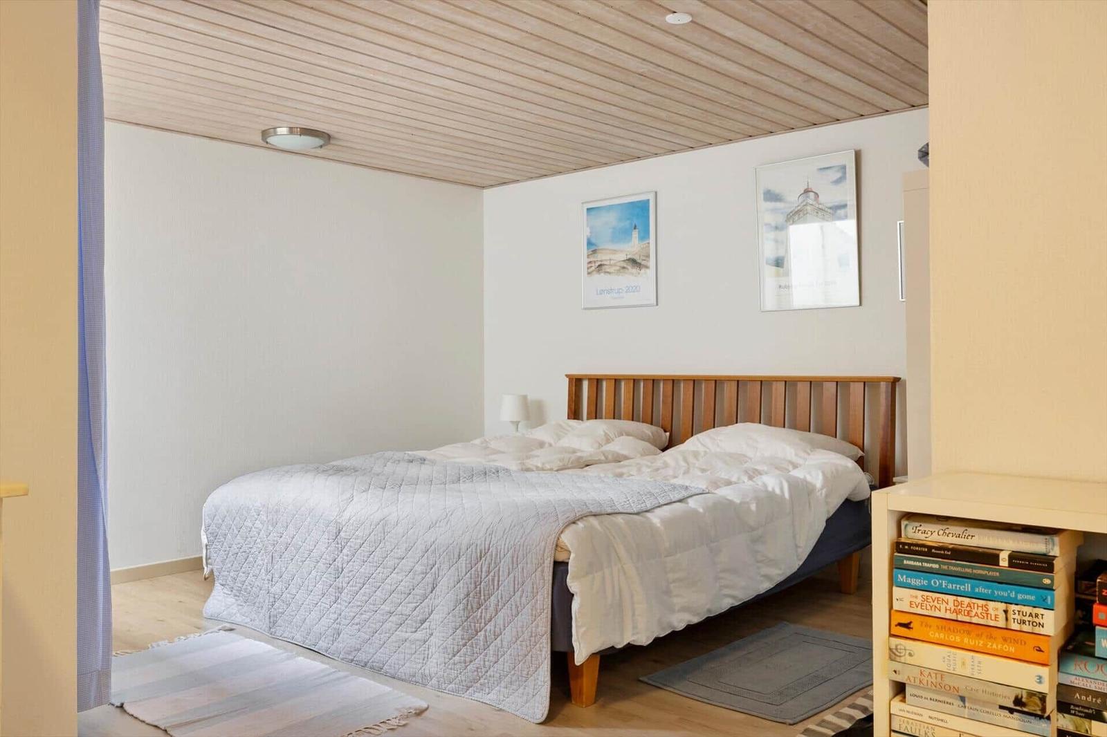 Schlafzimmer mit Bett, Holzdecke und Bildern an der Wand.