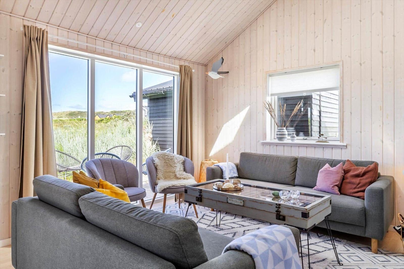 Wohnzimmer mit Sofa, Sesseln und großem Fenster zur Aussicht.