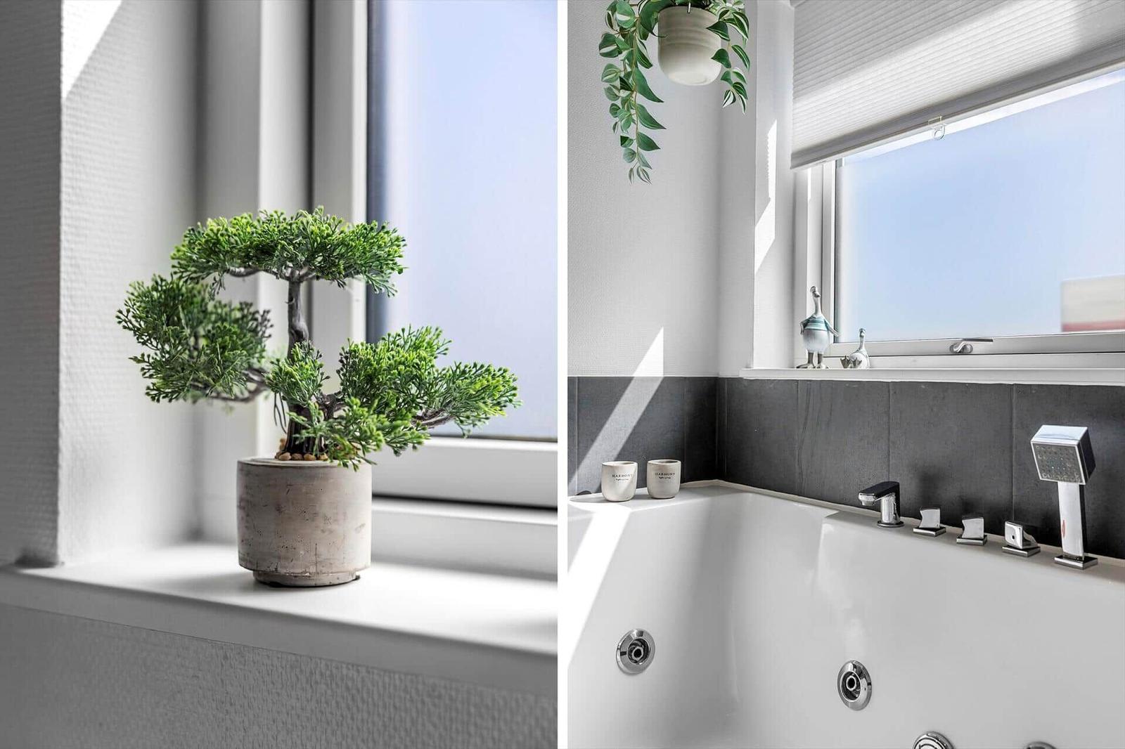 Badezimmer mit Badewanne, Fenster und Pflanzen