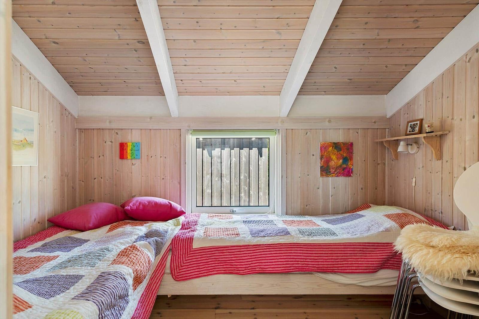 Zimmer mit zwei Betten, Holzwandverkleidung und Fenster mit Gitter.