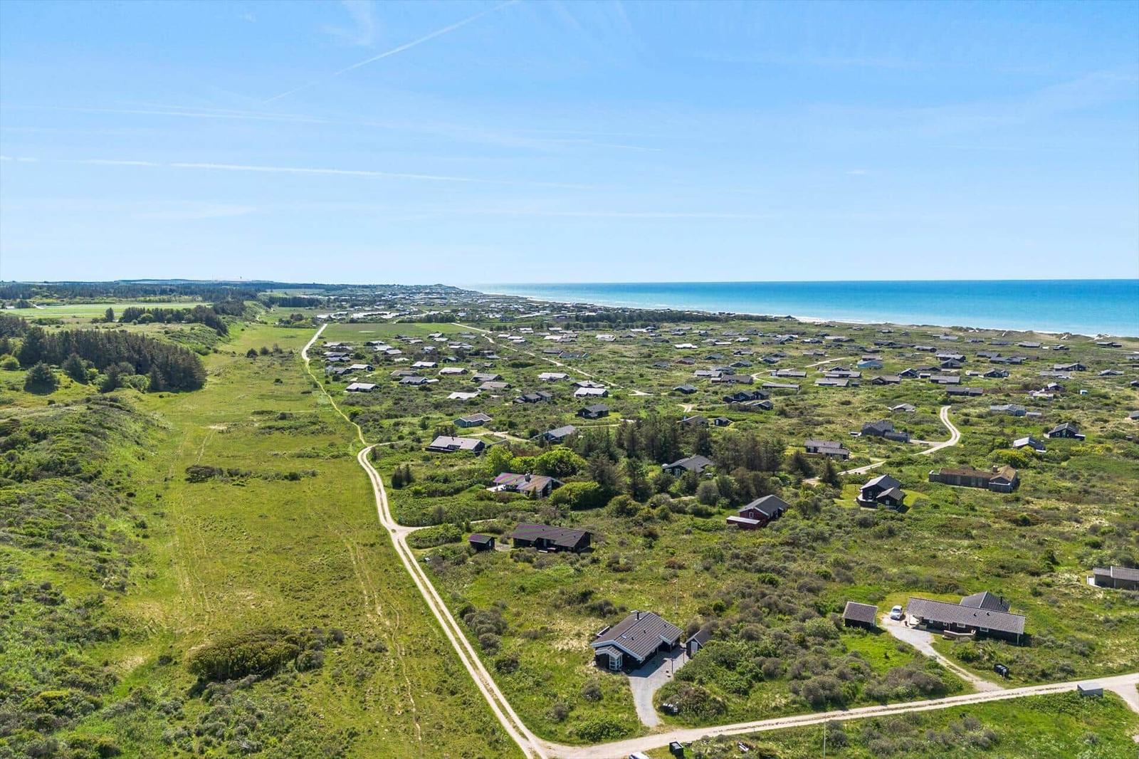 Luftbild einer Küstenlandschaft mit vielen Häusern und grünen Wiesen bis zum Meer.