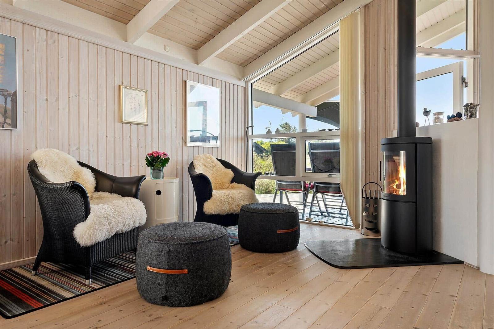 Zwei schwarze Sessel mit Felldecken, Kamin und Terrassentür im Wohnzimmer.