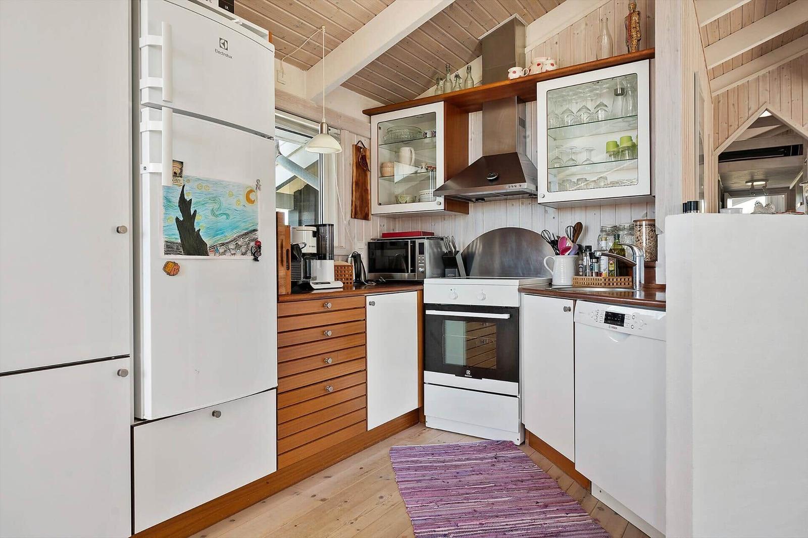 Küche mit Kühlschrank, Herd und Spülmaschine. Holzoberflächen und Glasregale.