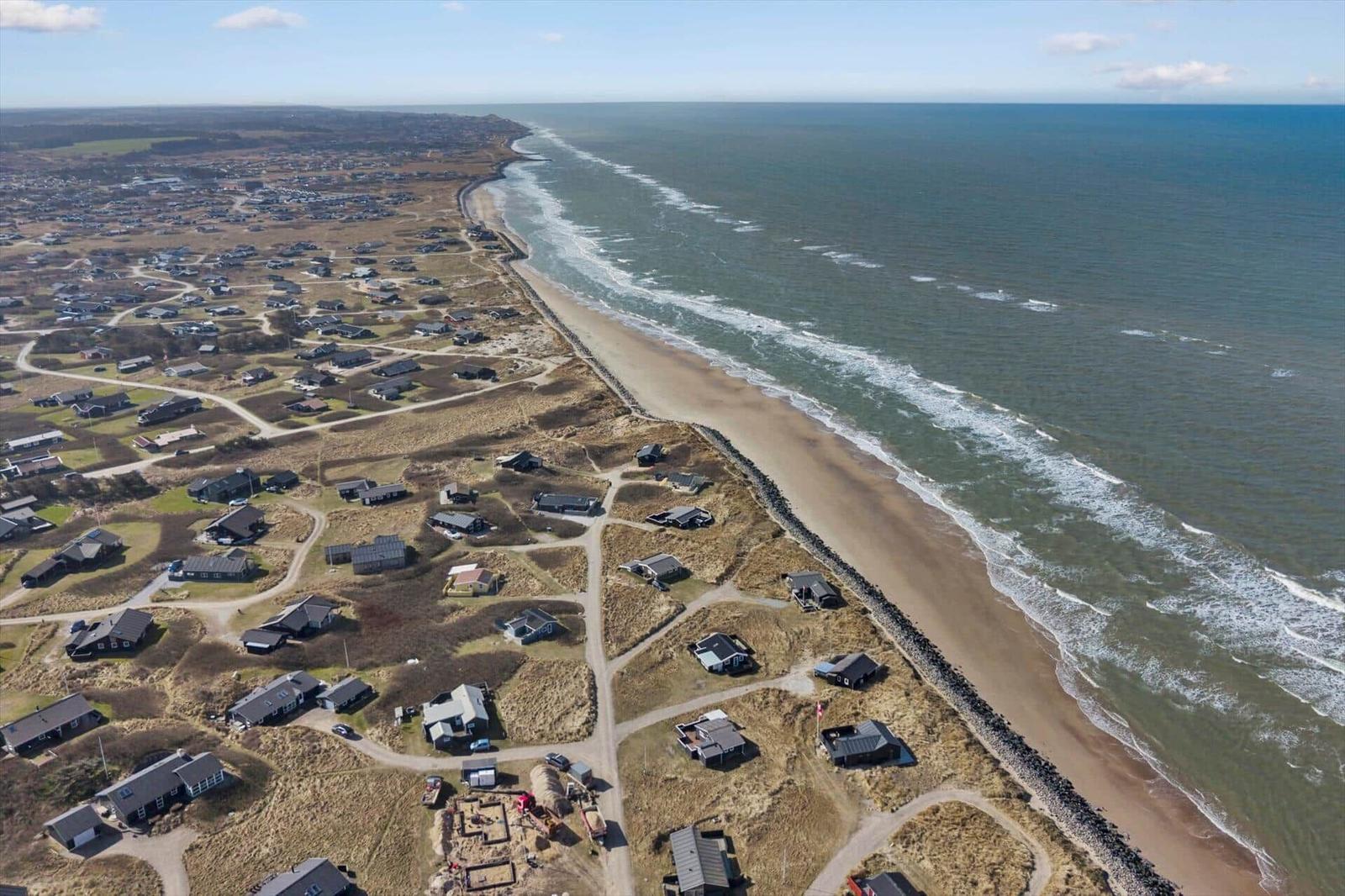 Aerial view of coastal village with houses along sandy beach and sea.