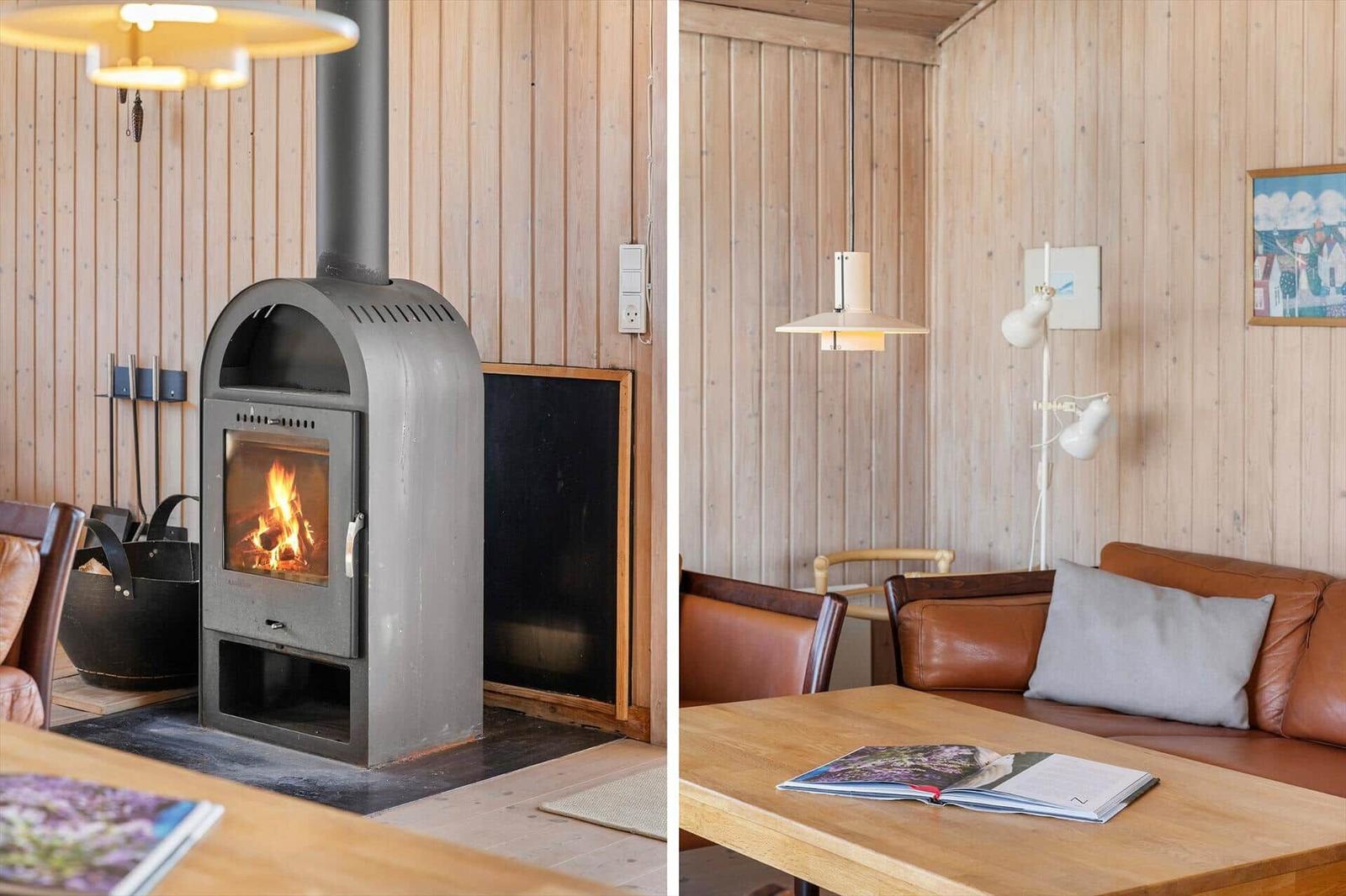 Wohnraum mit Holzwand, Kaminofen und Ledersofa. Tisch mit Buch und Lampen.