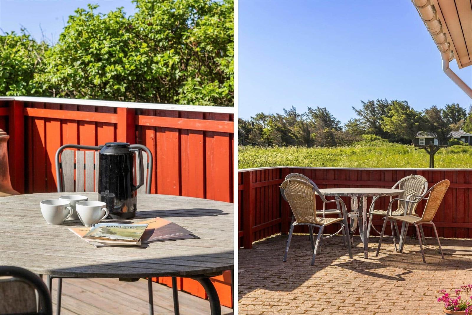 Terrasse mit Tisch und Stühlen, roter Zaun, grüne Bäume und Himmel