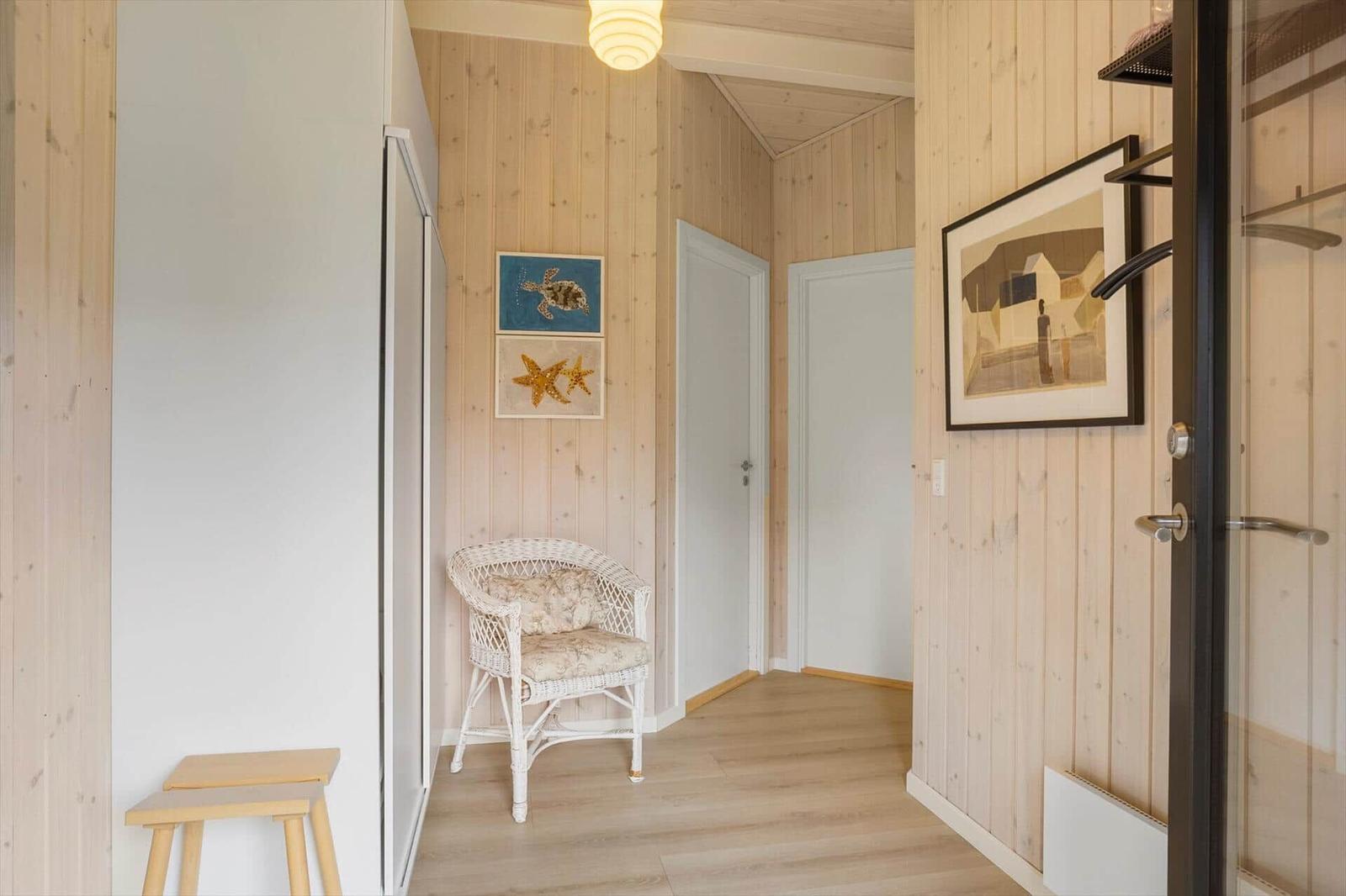 Hallenflur mit Holzwand, Stuhl und Bildern an der Wand.