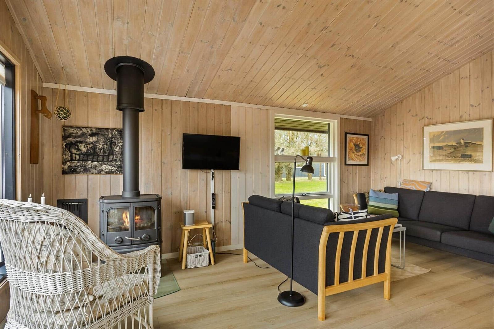 Wohnzimmer mit Kamin, Sofa und Fernseher an Holzwand