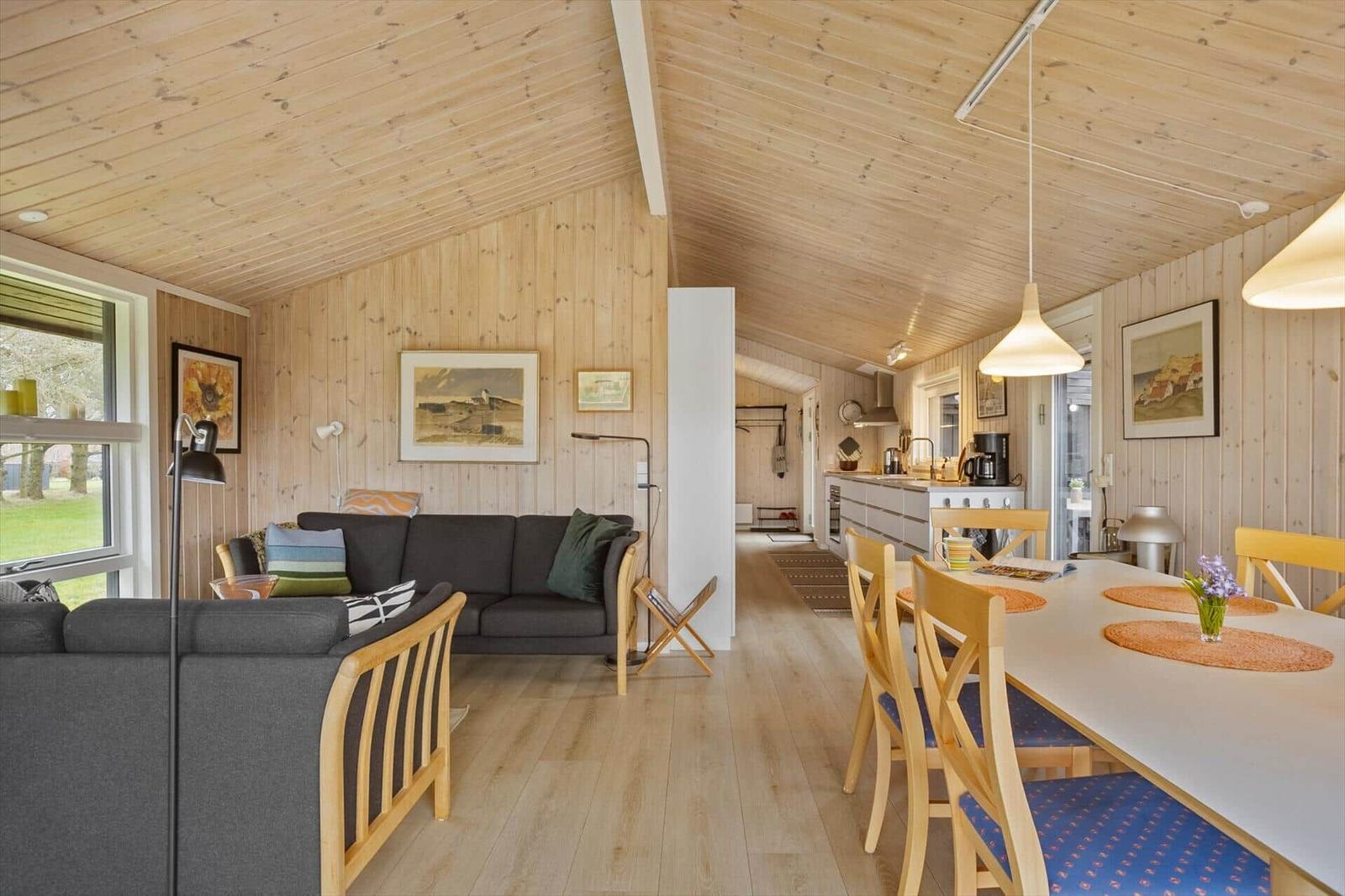 Wohn- und Essbereich mit Holzdecke, Sofa und Esstisch mit Stühlen.