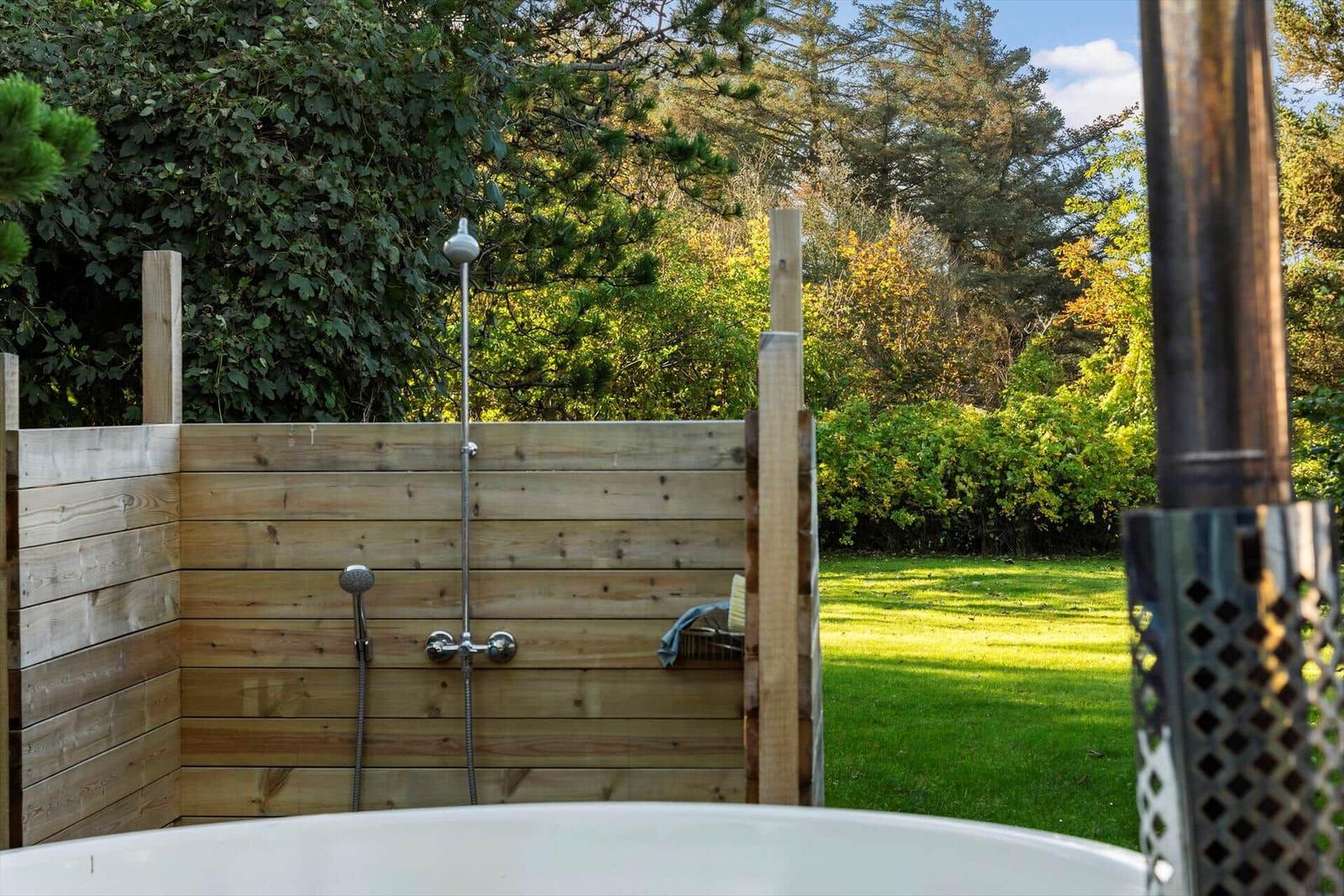 Außen-Dusche mit Holzwand und Duschbrause im Garten