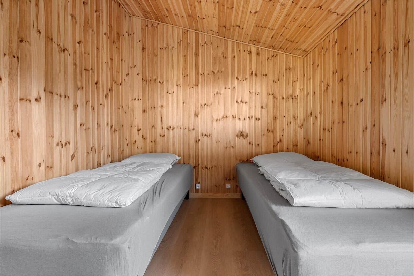 Zwei Betten in einem Holzraum mit Holzwandverkleidung und Holzboden.