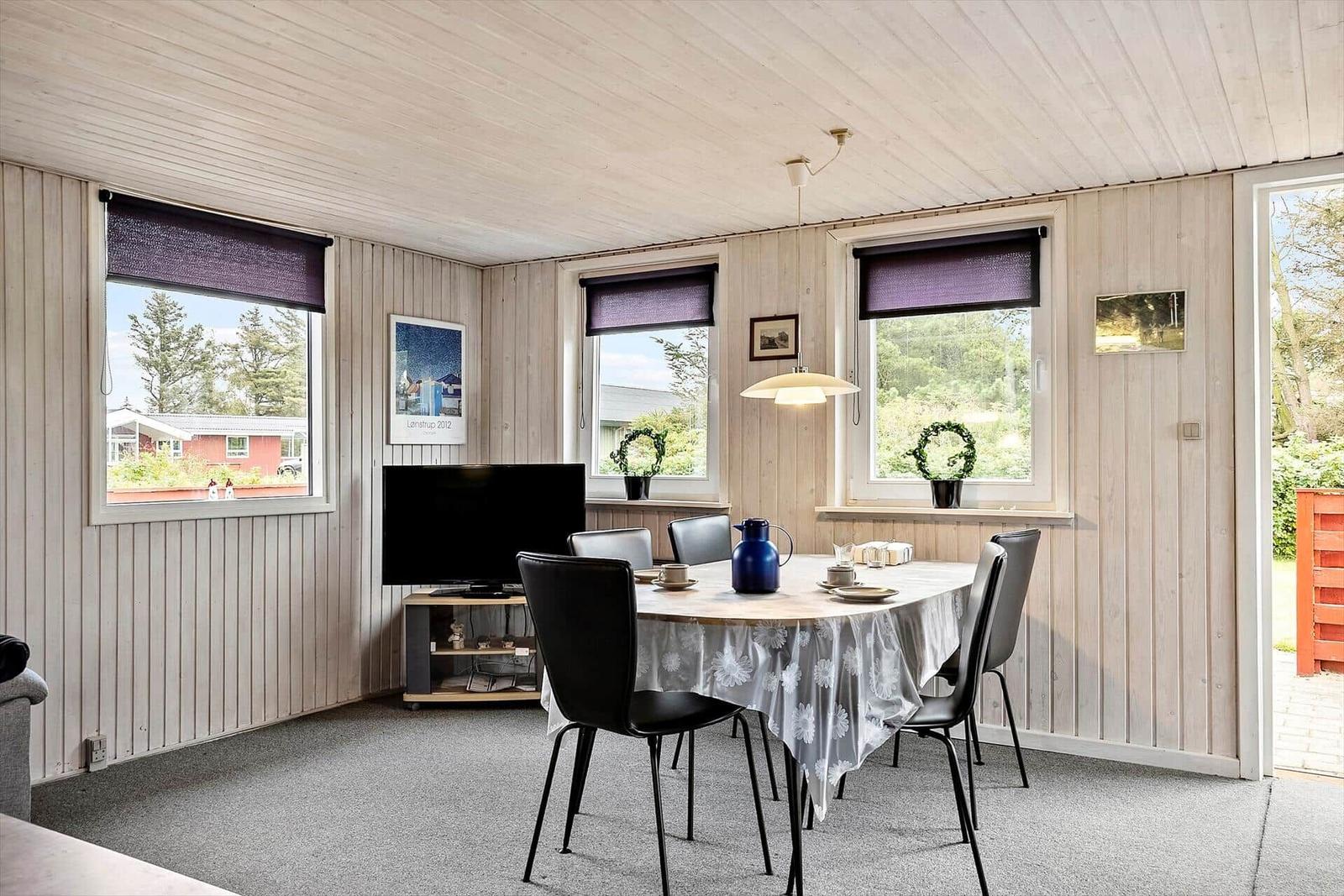 Esszimmer mit runden Tisch, schwarzen Stühlen und Fenstern mit lila Rollos.