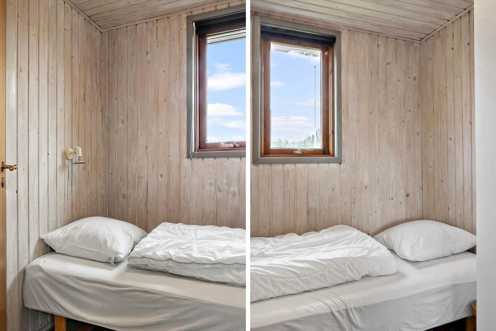 Ein Schlafzimmer mit Holzwand, Bett und Fenster. Blick auf den Himmel.