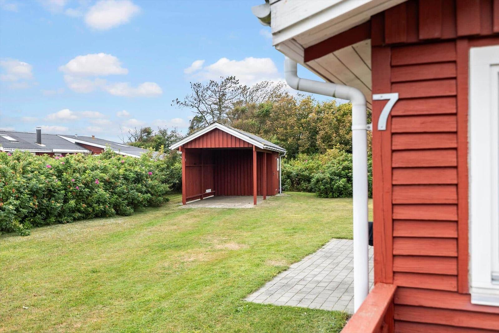 Roter Holzaufbau mit Garten und Pavillon im Hintergrund.