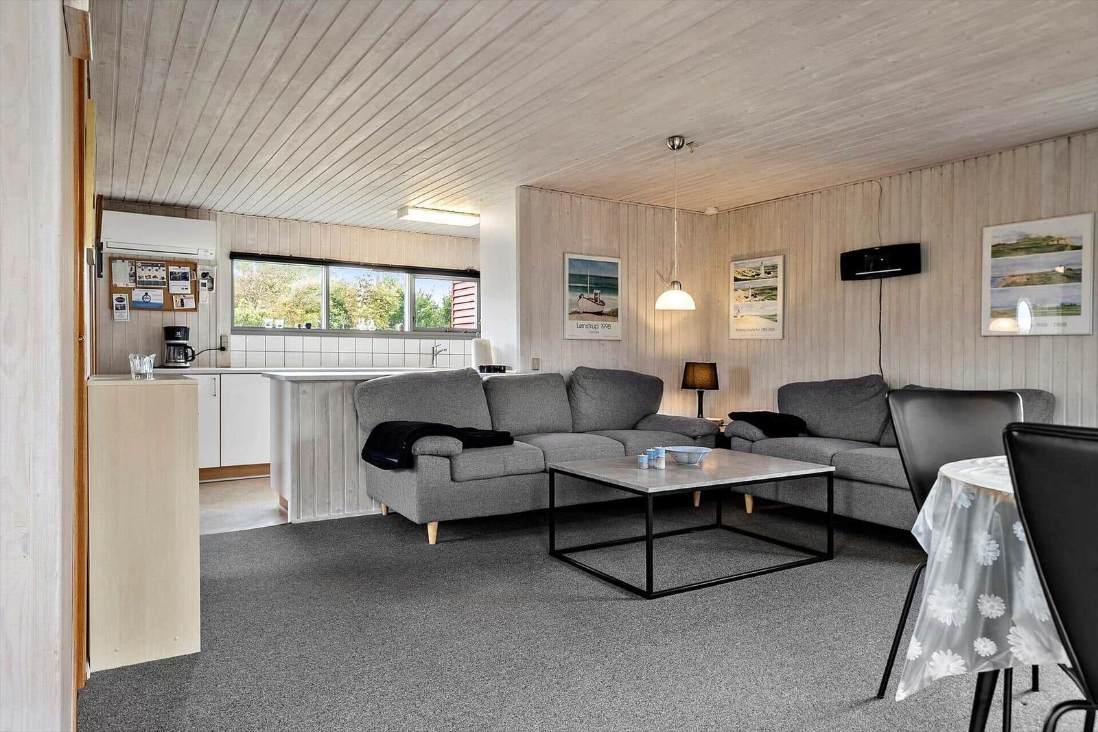 Wohnzimmer mit zwei Sofas, Tisch und Küchenbereich mit Fenster.