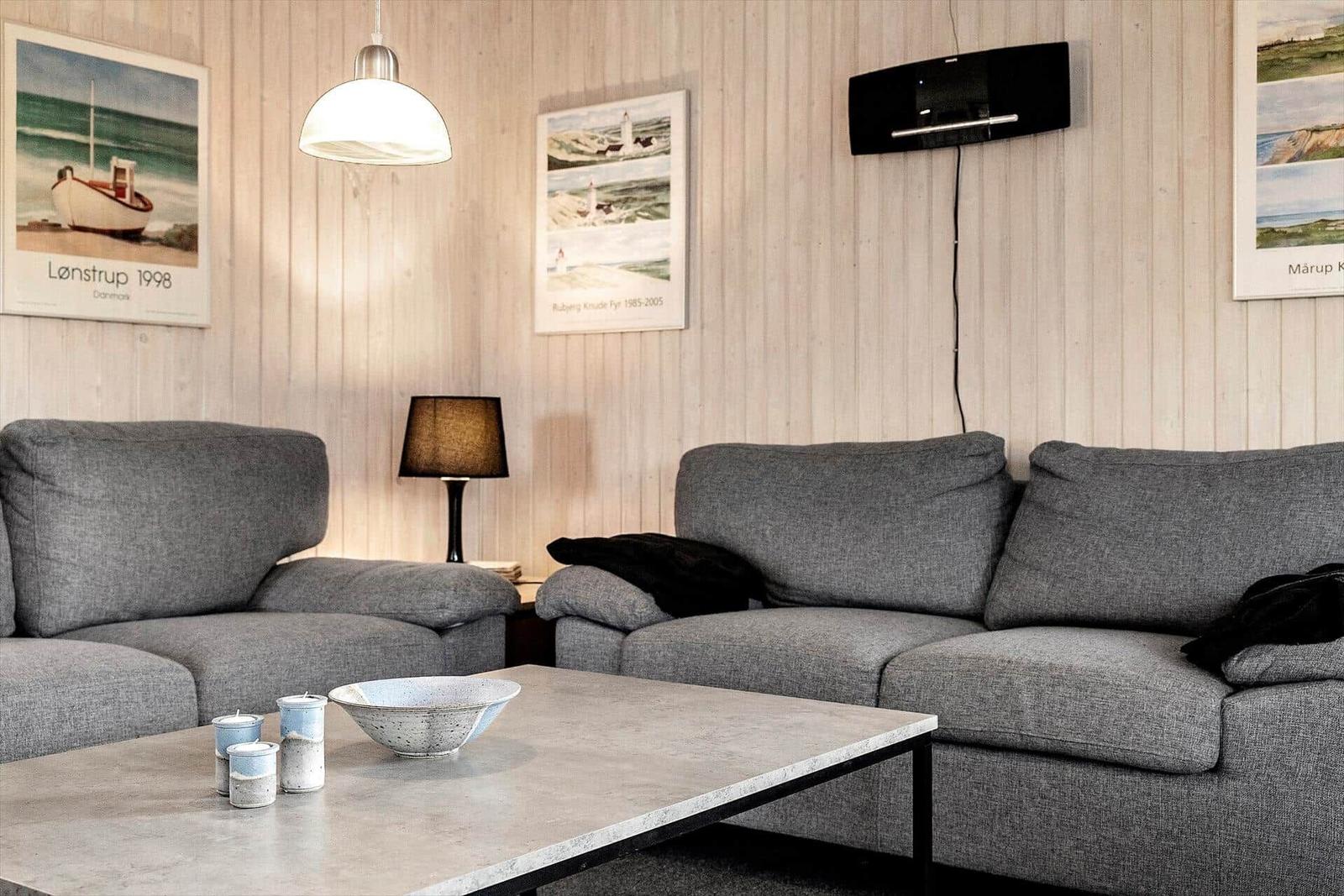 Wohnzimmer mit grauem Sofa, Tisch und Wandbildern