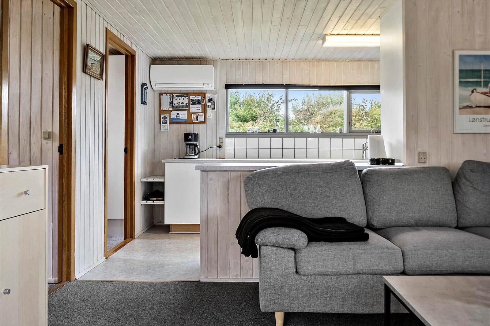 Wohnbereich mit Sofa, Küchenzeile und Fenster zum Garten.