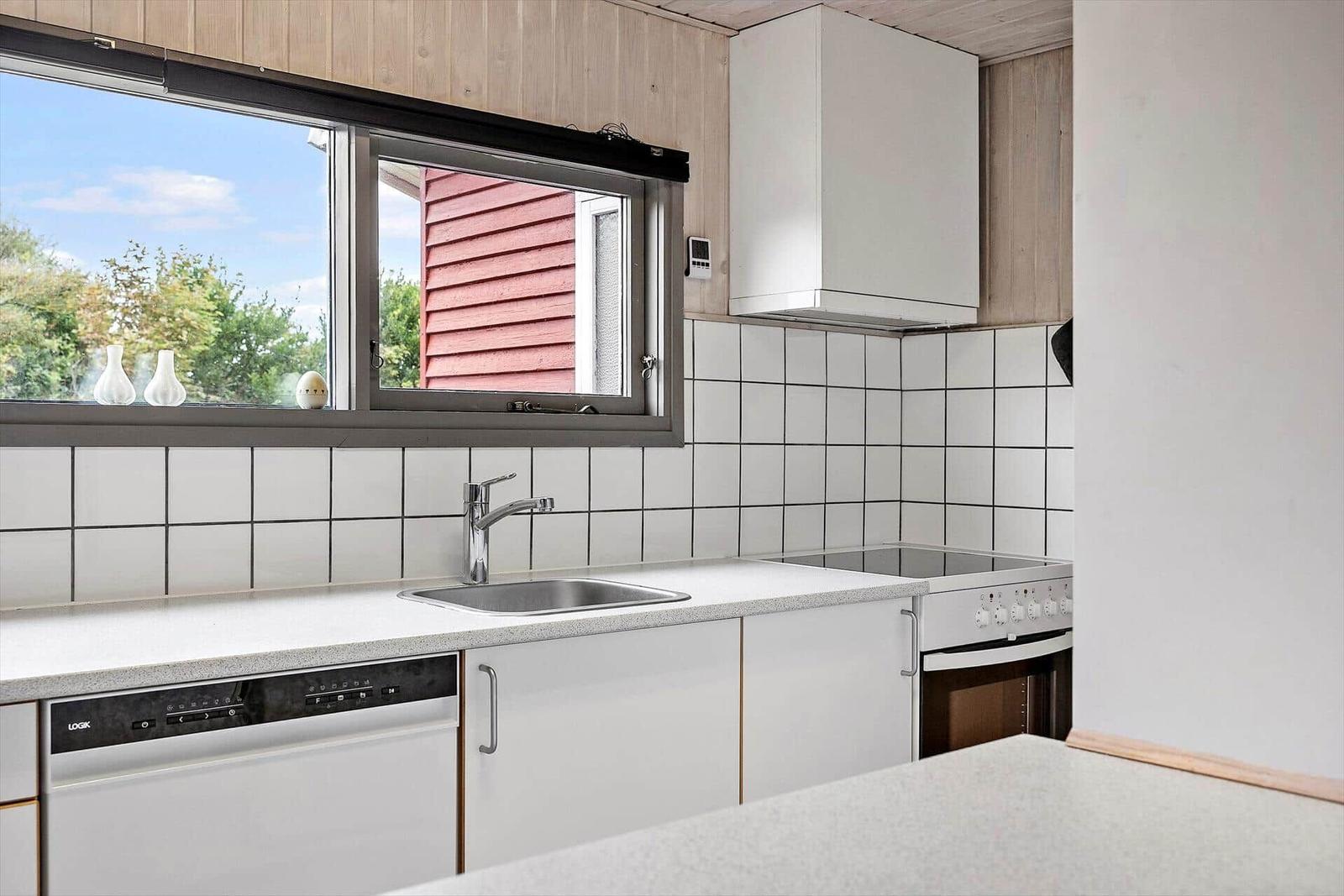 Küche mit Spüle, Herd und Fensterblick auf Außenbereich
