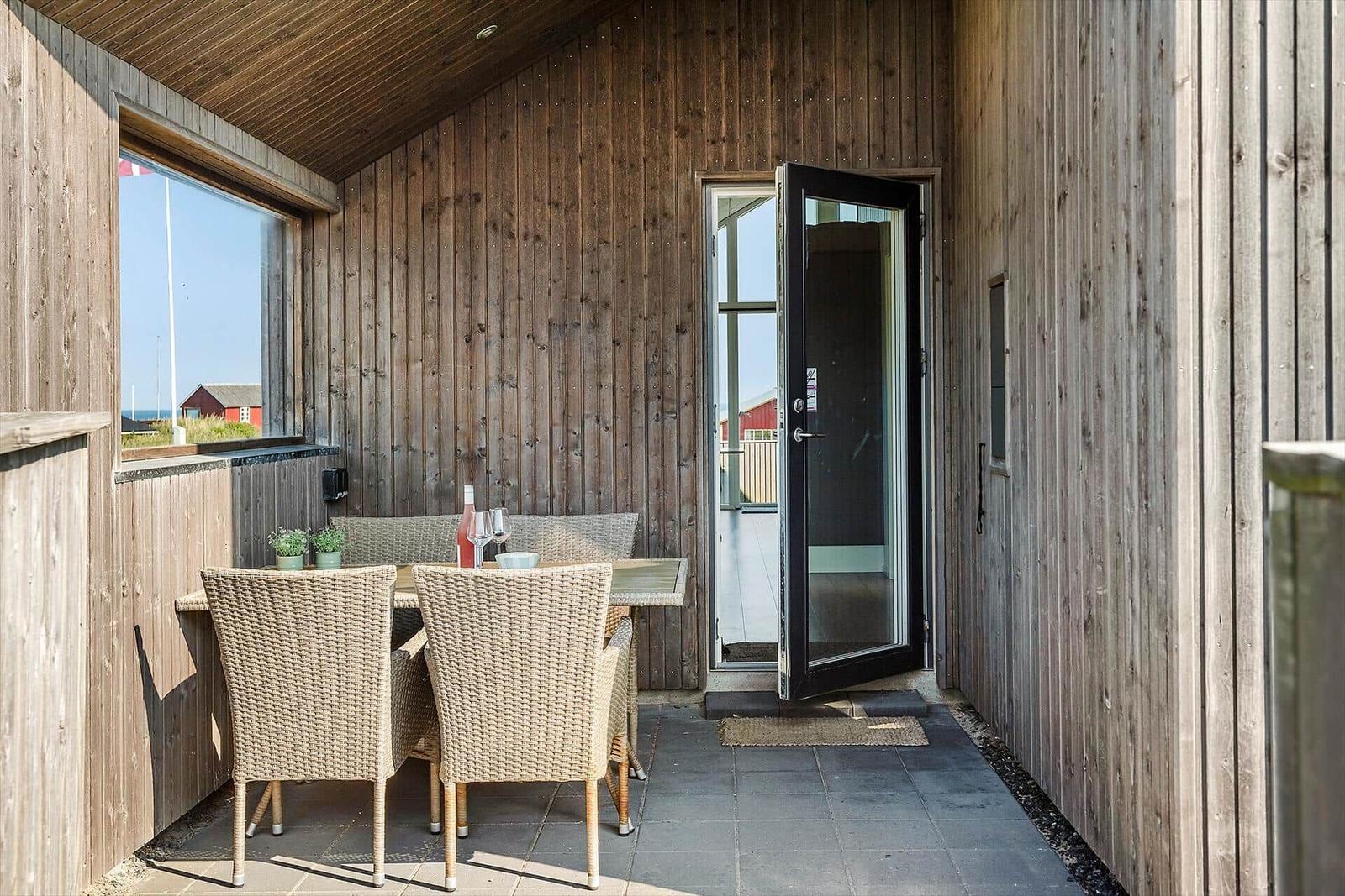 Terrasse mit Tisch, Stühlen und Blick auf das Meer.