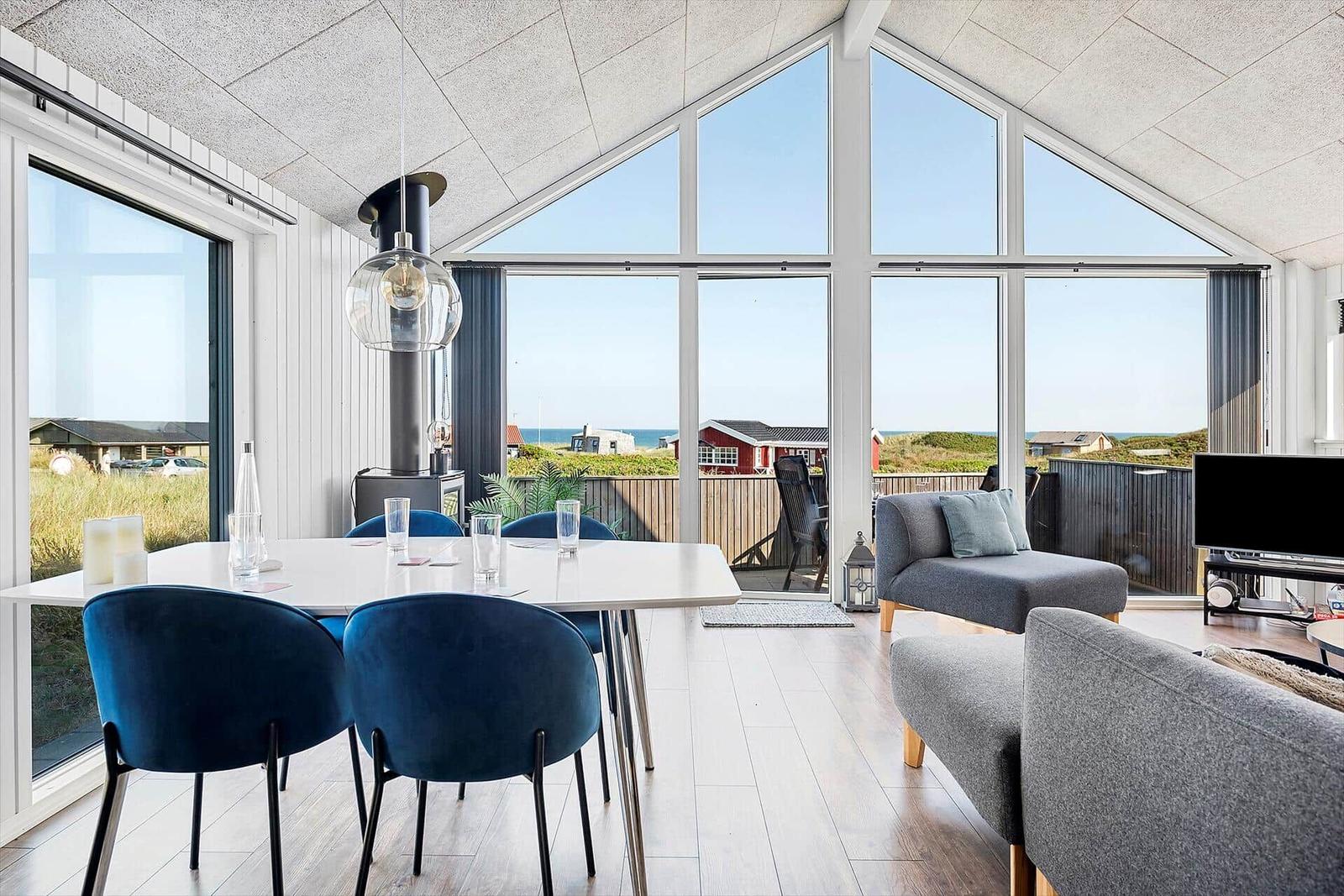 Modern eingerichtetes Wohn- und Esszimmer mit Blick auf den Strand.