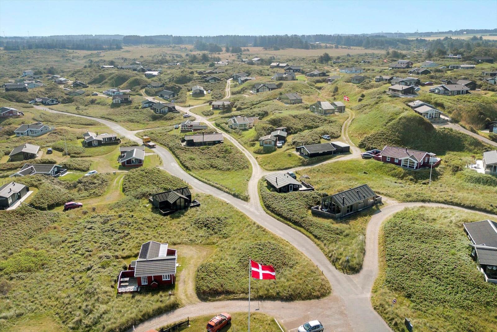 Aerial view of a Danish village with scattered houses on grassy hills and winding roads.