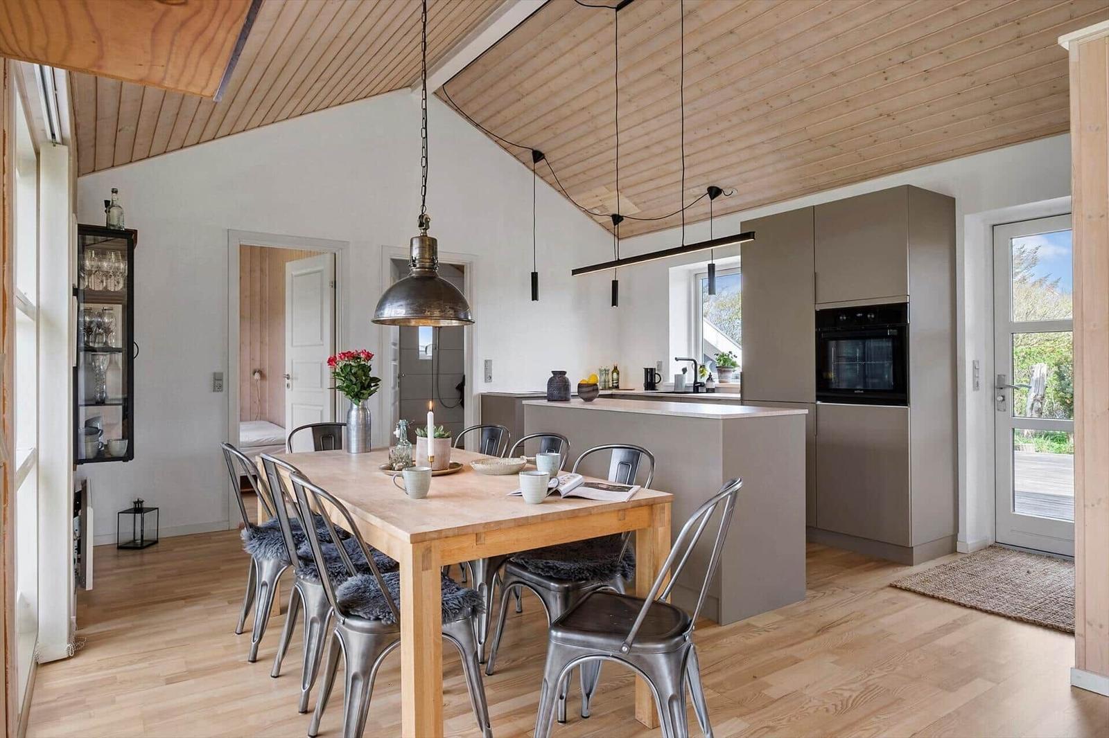 Küche und Essbereich mit Holzdecke, Tisch und Stühlen. Durchgang zu Schlafzimmer.