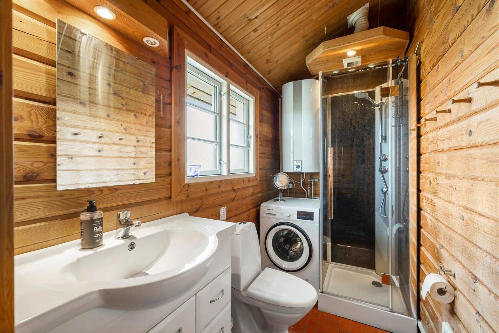 Badezimmer mit Dusche, Waschmaschine und Holzwandverkleidung.