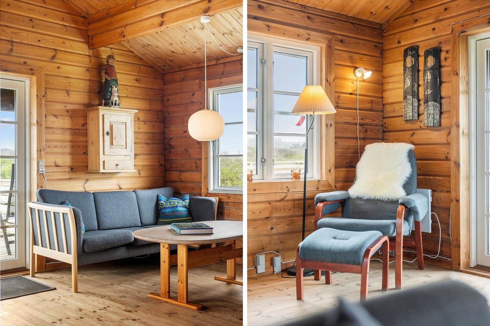 Wohnraum mit Holzwand, Sofa, Tisch und Sessel mit Fellkissen.